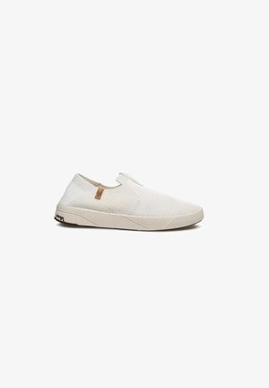 Zapatilla deportiva blanca sin cordones con parte superior de punto texturizado, suela beige y pequeña etiqueta de logo marrón cerca del cuello sobre fondo blanco.