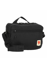 Svart nylon skulderveske med topphåndtak, justerbar stropp, glidelåslomme foran og logo-patch. Glatt tekstur og rektangulær form.