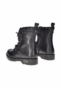 Stivaletti neri in pelle con dettagli arricciati, occhielli in metallo, zip laterali e suole in gomma texturizzata. Accento con logo sul tallone.