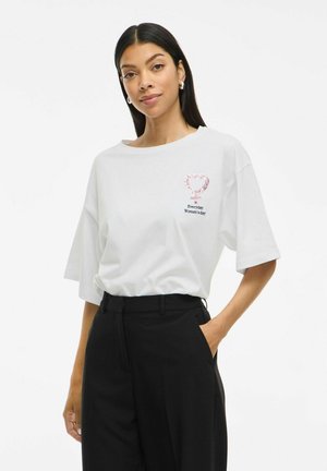 T-shirt en coton blanc avec une coupe décontractée, présentant un graphique de cœur rose et le texte "Journée des Femmes Quotidienne" sur la poitrine gauche.