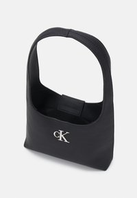 Borsa a mano nera in nylon con manico corto, caratterizzata da una sottile texture ripstop e un logo "CK" argentato sul fronte. Design aperto.