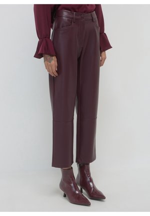Pantalon en faux cuir bordeaux taille haute, associé à des bottines assorties à bout pointu et un chemisier à manches longues à volants.