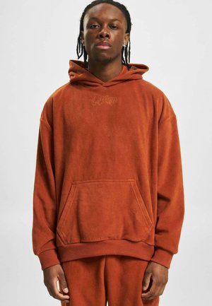 Hanorac din fleece portocalie cu un buzunar frontal tip kangaroo, manșete și tiv cu ripuri, având un logo brodat pe piept. Textură moale.