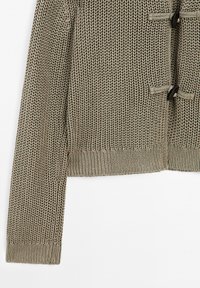 Stickad tröja i en taupe-färg med en texturerad mönster, som har två togglekknappar samt ribbad mudd och fåll.