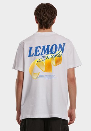 Person som har på seg en hvit t-skjorte med stor blå "LEMON soda"-tekst og en gul sitronskallgrafikk på baksiden.