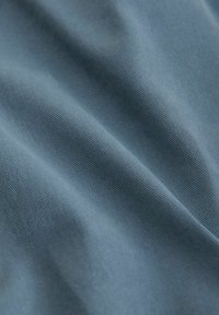Tela azul texturizada con finas estrías visibles, dispuesta para mostrar suavidad y profundidad. Adecuada para uso en confección de prendas o tapicería.