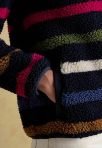 Pullover with multicolored stripes in pink, green, blue, navy, and brown; made of soft, textured fleece with a pocket and ribbed cuffs.