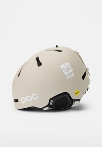 Skihelm in mattem Beige, mit Belüftungsöffnungen, weißen Logos und schwarzen Akzenten. Enthält MIPS-Technologie für zusätzliche Sicherheit.