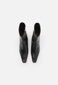 Bottines en cuir noir avec une texture crocodile, bout pointu et détail de fermeture éclair dorée, présentant une doublure intérieure lisse.