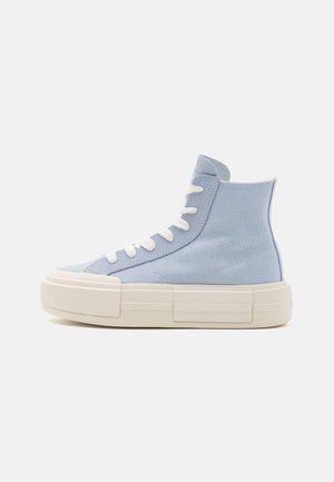 Jasnoniebieski sneaker typu high-top z białymi sznurowadłami i grubą, kremowo-białą gumową podeszwą, pokazany z boku na jednolitym tle.