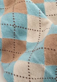 Blaues, beiges und braunes Argyle-Muster auf einem Stoff mit strukturiertem Oberflächen und kontrastierendem Nähen, das weiche, gewebte Fasern zeigt.