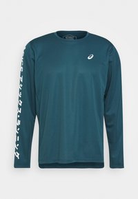 Langarm-Sportshirt aus tealfarbenem Stoff. Mit Rundhalsausschnitt, weißem Logo auf der Brust und weißem Text entlang des linken Ärmels.