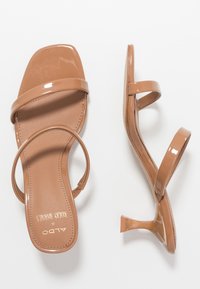 Bruna lackläderklackar med fyrkantig tå, två tunna remmar och en låg stilettklack. Texturerad innersula för komfort.