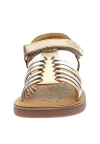 Sandalia de oro y plata con un diseño de tiras, correa de tobillo ajustable y plantilla texturizada con un patrón floral. Suela plana de goma.