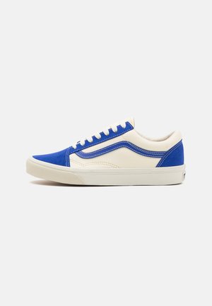 Blue and cream sneaker with a canvas upper, contrasting blue accents, padded collar, and white rubber sole. Features flat laces and stitch detailing.