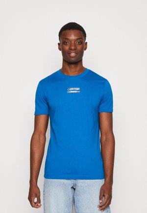 Bright blue short-sleeve t-shirt, made from soft fabric, featuring a white Calvin Klein Jeans logo on the chest, round neckline.