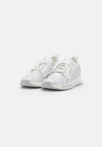 Ein Paar weiße Sportschuhe mit grauen geometrischen Mustern, aufgebundenen Schnürsenkeln und "DKNY"-Logo an der Seite und Sohle, vor einem schlichten weißen Hintergrund.