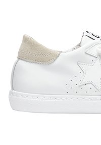 Sneaker bianca in pelle con accentuazione in suede beige sul tallone, design a stella, motivo perforato e suola in gomma bianca testurizzata. Chiusura con lacci semplice.