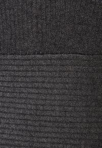 Mörkgrått tyg med en ribbad textur högst upp och ett randigt mönster längst ner, vilket skapar en tydlig avskiljning.