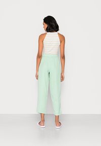 Top de halter listrado com calças relaxadas de tom verde claro. O material parece suave e leve, apresentando uma cintura elástica. Design simples.