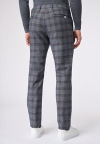 Dopasowane, szare, w kratę spodnie wykonane z teksturowanej tkaniny. Posiadają kieszenie z tyłu oraz slim-fit, zestawione z białymi trampkami.