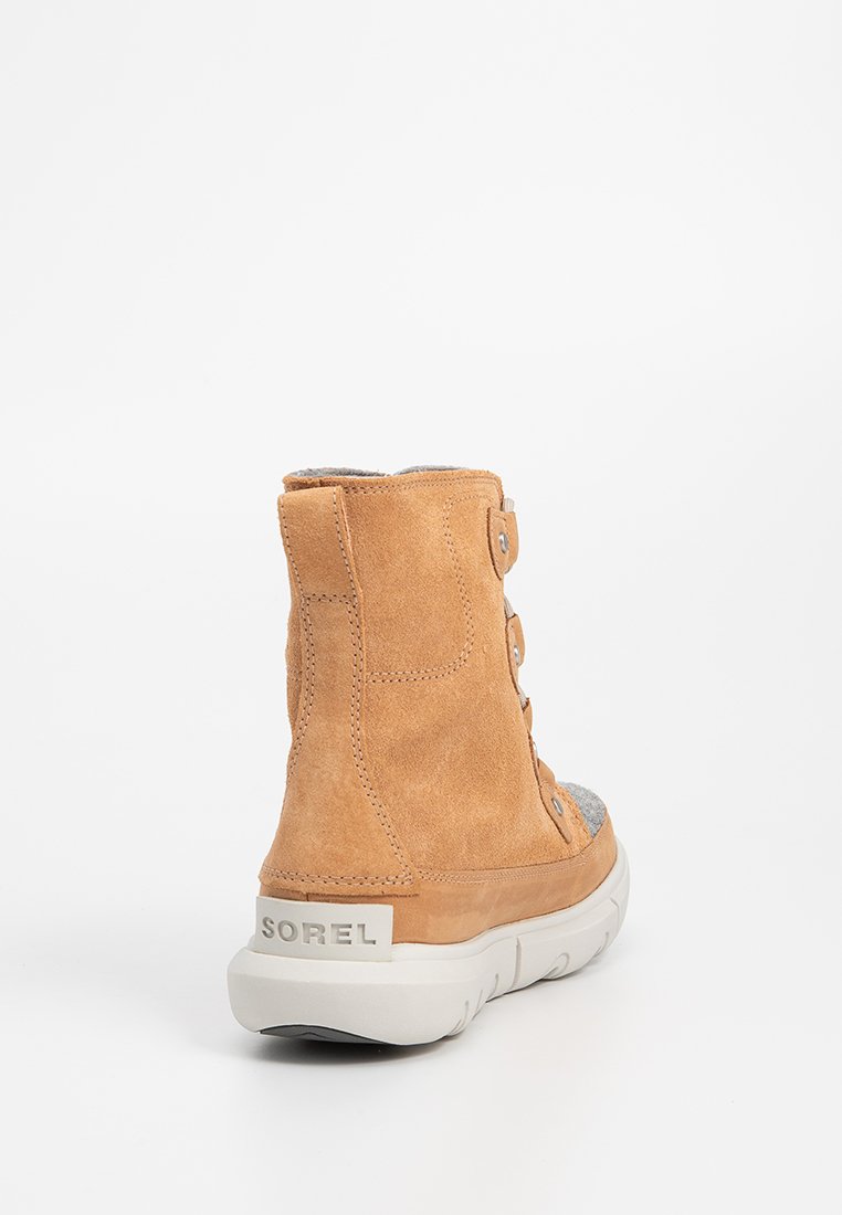 Botte de cheville en daim tan avec des accents textiles gris, dotée d'un bout arrondi, d'une doublure en tissu et d'une semelle en caoutchouc blanche. Comprend des détails en boutons.