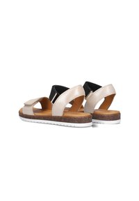 Beige leren sandalen met zwarte elastische band, open teen en gevoerd kurken voetbed. Witte rubberen zool met een gemêleerd patroon.