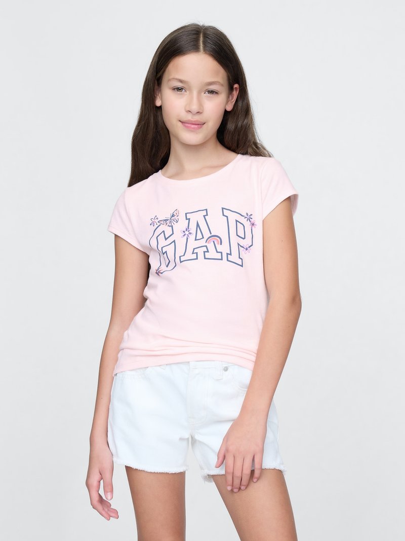 Light pink cotton t-shirt with "GAP" logo printed in dark blue, short sleeves, paired with white denim shorts with frayed edges.