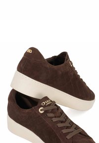 Brown suede sneakers with a textured upper, white platform sole, gold logo accents, and brown laces. Features a rounded toe design.