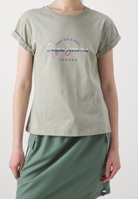 Kaki grön bomullströja med uppvikta ärmar, med "The Original Pepe Jeans London" i färgglad text över bröstet.