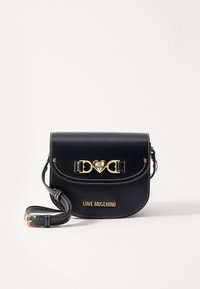 Black leather crossbody bag with gold heart-shaped hardware, curved flap, white stitching, and "LOVE MOSCHINO" branding on the front.