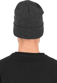 Gray knit beanie with a folded cuff. The texture is smooth and tightly woven, showing a slight ribbed pattern. The model wears a black shirt.