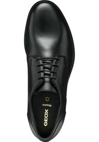 Scarpa di pelle nera con una texture liscia, punta arrotondata, design con lacci e logo dorato "GEOX" sulla soletta. Stile classico.