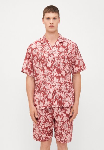 Rød blomstret kortærmet skjorte og matchende shorts, lavet af letvægtsstof. Har et gentaget blomstermønster i nuancer af pink og rød.