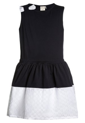 Mouwloze jurk met een zwarte katoenen top en een witte kantonderkant. Bevat twee kleine witte accenten op de schouder en een geplooide taille.