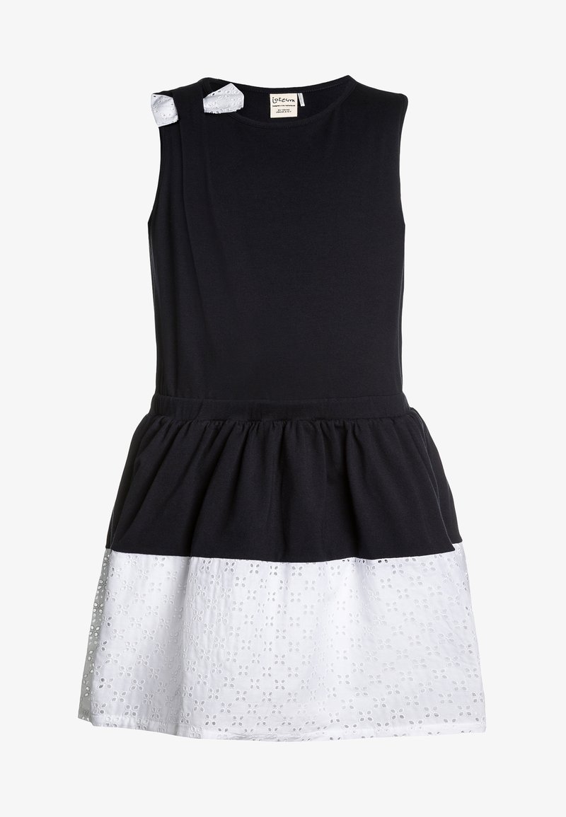Robe sans manches avec un haut en coton noir et un bas en dentelle blanche à motifs. Comprend deux petits accents blancs sur les épaules et une taille froncée.