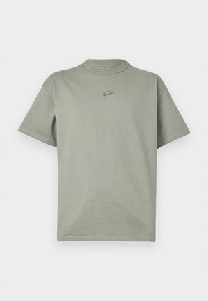 T-shirt en coton gris clair avec un col rond et des manches courtes. Présente un petit logo Nike brodé sur la poitrine.
