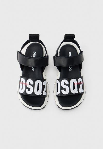 Μαύρα σανδάλια με δύο φαρδιές λουρίδες που φέρουν το λευκό λογότυπο "DSQ2", με επένδυση σόλας που προσφέρει άνεση και χοντρή λευκή σόλα με μαύρες λεπτομέρειες.