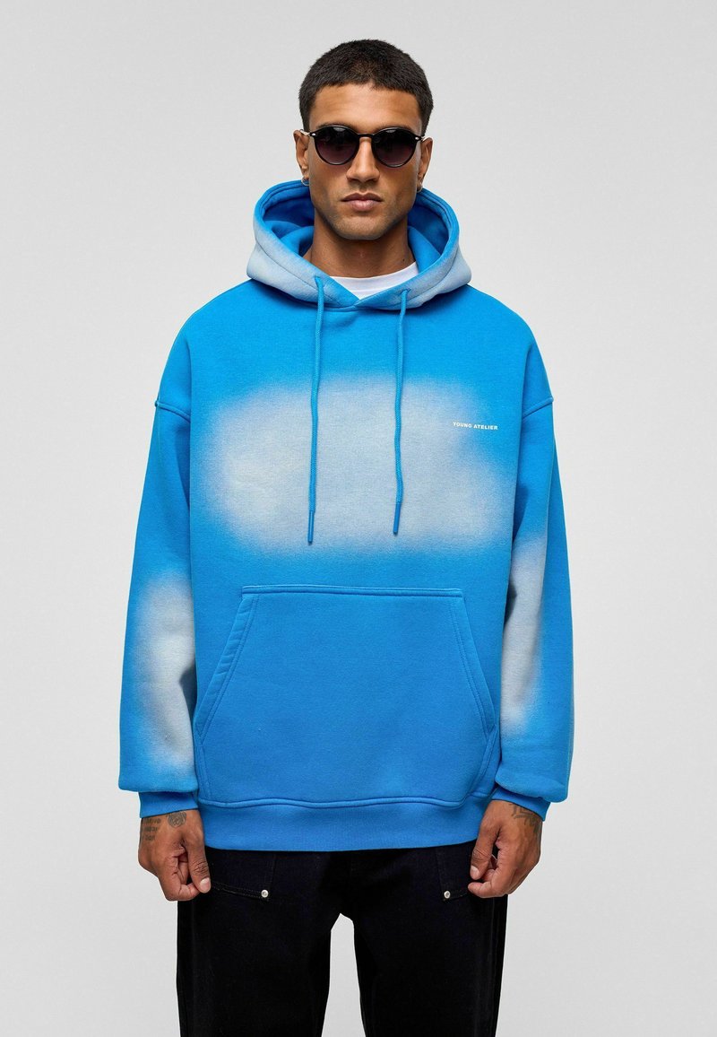 Blauwe hoodie met een ombre-ontwerp dat overgaat in lichtblauw, voorzien van een voorzak en een capuchon met trekkoord. De stof lijkt zacht te zijn.