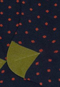 Calzini blu navy con piccoli pois arancioni e talloni verde oliva, con texture a maglia e dettagli di cucitura.