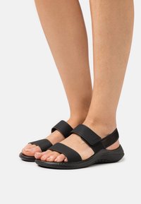 Sandali neri con due fasce larghe e una superficie texture, dotati di suola imbottita e design aperto per una migliore traspirabilità.