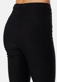 Slim-fit zwarte broek van textiel met twee achterzakken en een middelhoge taille. De op maat gemaakte pasvorm benadrukt de vorm.