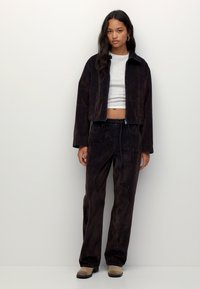 Tumman pehmeä samettinen lyhyt takki ja yhteensopivat housut; harmaa kapea paita alla; lisätieto: musta vetoketju housuissa.