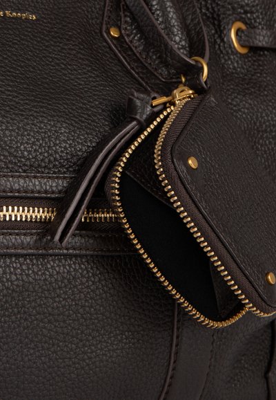 Bruine leren handtas met een getextureerd oppervlak, gouden metalen accenten en een detail met een ritssluiting. Voorzien van een kleine rits en stiknaden.