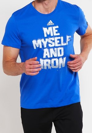 Man die rent en een blauwe Adidas T-shirt draagt met witte tekst "ME MYSELF AND IRON" en zwarte broek.