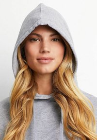 Grijze hoodie met een zachte textuur, voorzien van een trekkoord en een grote, ronde capuchon. Licht gemêleerde stof.