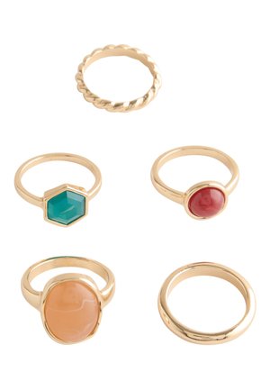 Five gold rings with different designs including twisted band, plain band, and bands with red, green hexagon, and large oval beige stones.