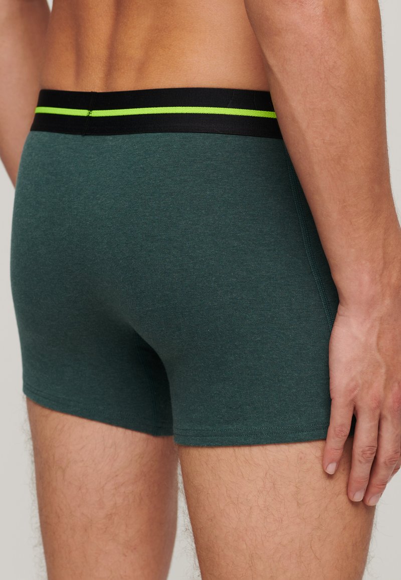 Teal boxershorts met een zwarte tailleband met een groene accentstreep. Gemaakt van een zachte, gestructureerde stof, hebben ze een aansluitende pasvorm.