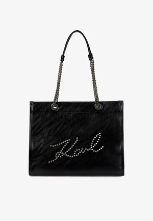 Svart skinnveske med teksturert overflate, med sølvfargede kjedehåndtak og nagledekorasjon som staver "Karl" på forsiden.