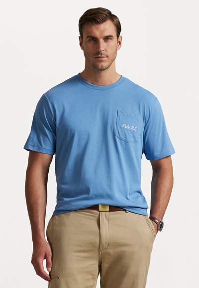 T-shirt en coton bleu clair à manches courtes avec un col rond, présentant une poche poitrine et un logo "Polo RL" brodé en blanc.